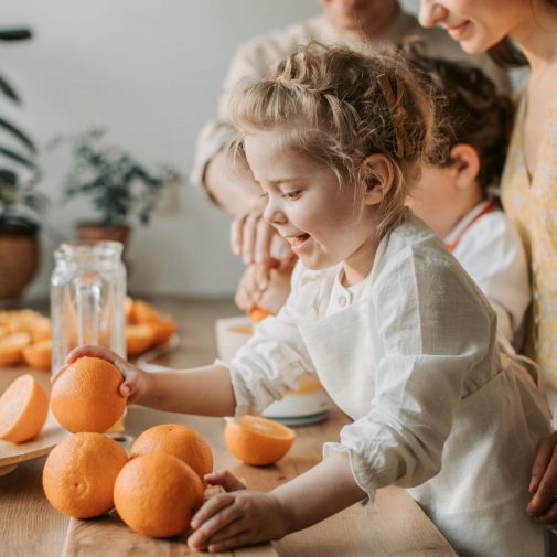 Joyful family with children making fresh orange juice in a bright kitchen setting.